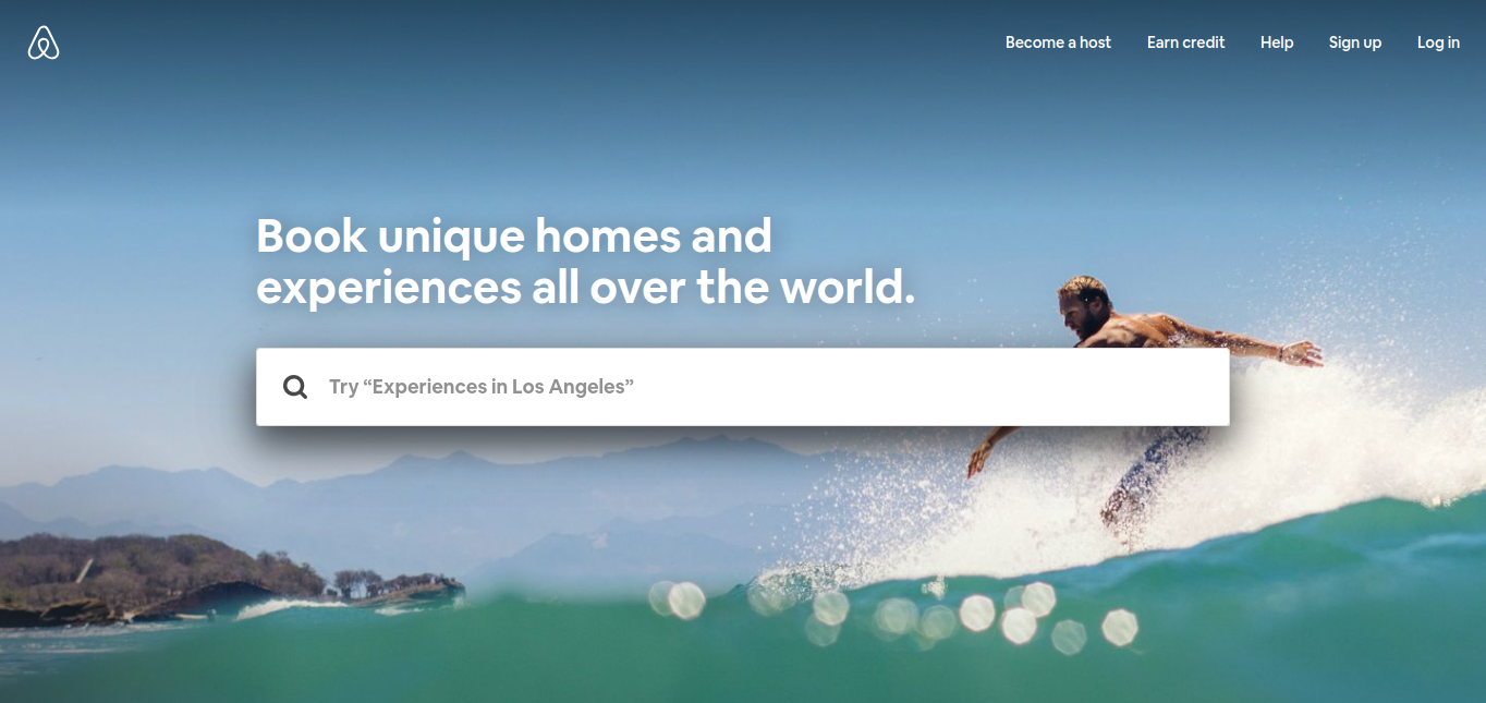 Hero image of a surfer in action with mountains in behind and the Airbnb search bar overlay